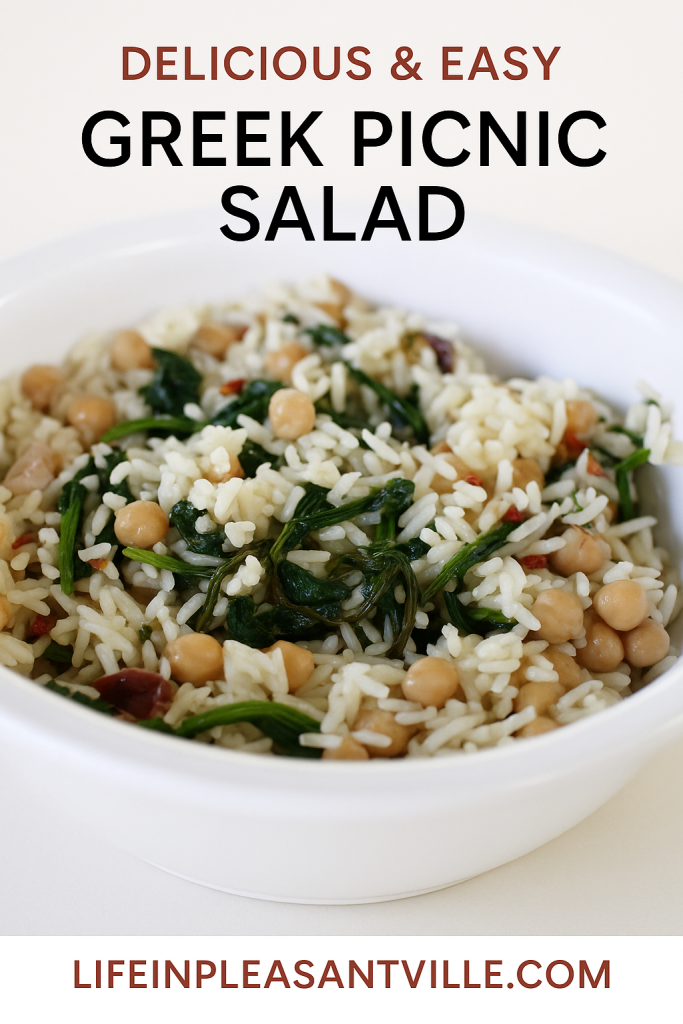A white bowl filled with Greek Picnic Salad made with rice, chickpeas, spinach, and sun-dried tomatoes, set against a light background with bold text that reads “Delicious & Easy Greek Picnic Salad” and the website “lifeinpleasantville.com” at the bottom.
