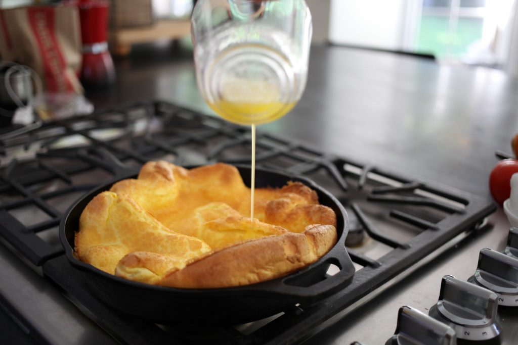 Drizzle clarifed butter over Dutch Baby before sprinking with lemon and powdered sugar. 