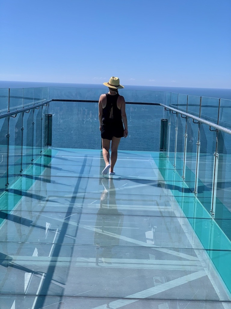 Woman standing on the glass observation deck at El Faro Lighthouse in Mazatlán Mexico overlooking the Pacific Ocean.