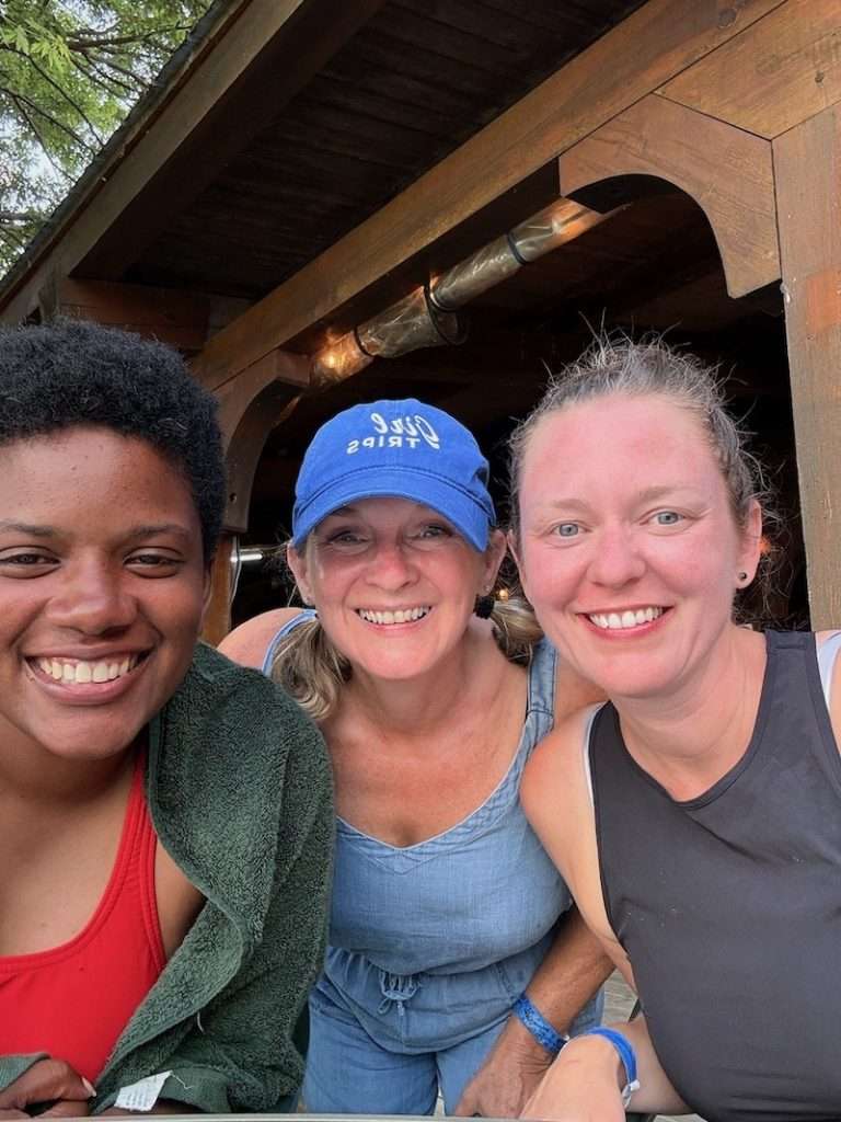 Three women smiling together under the pavilion at OWL Rafting, including a solo traveller visiting Canada from New Jersey