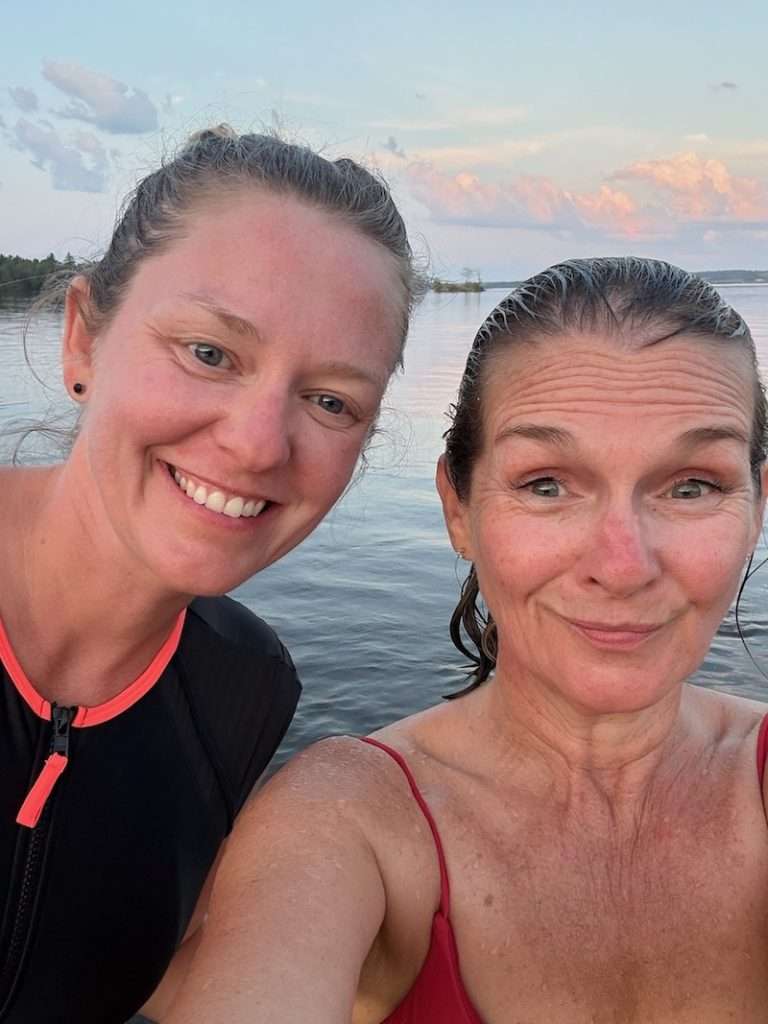 Two women smiling in a lake at sunset after a day of white water rafting on the Ottawa River