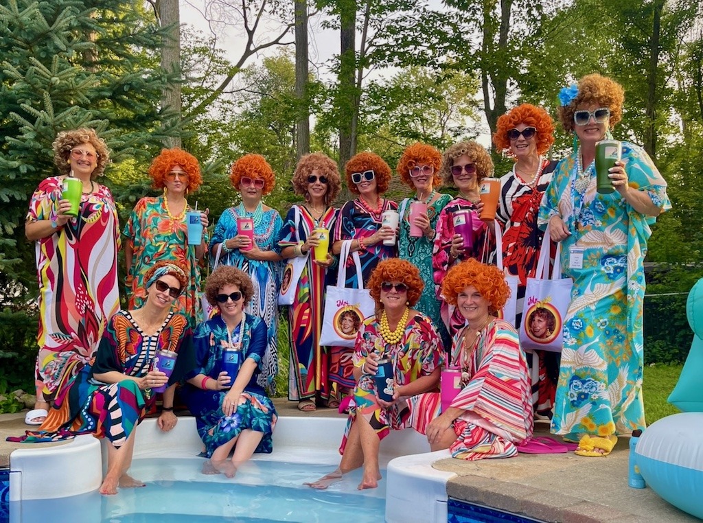 Guests dressed for a Mrs. Roper party wearing caftans, wigs, and oversized sunglasses.