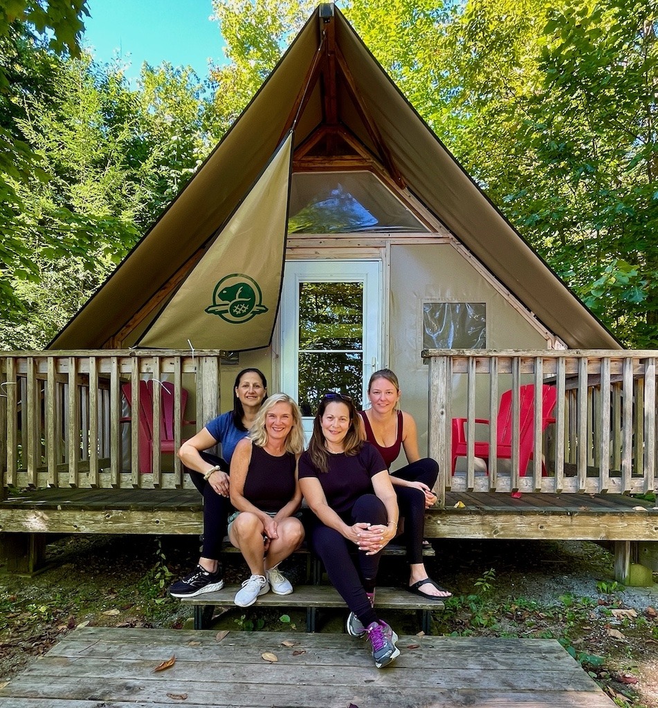 Group of women at Parks Canada oTENTik site on a girls’ camping trip in Ontario at Beausoleil Island