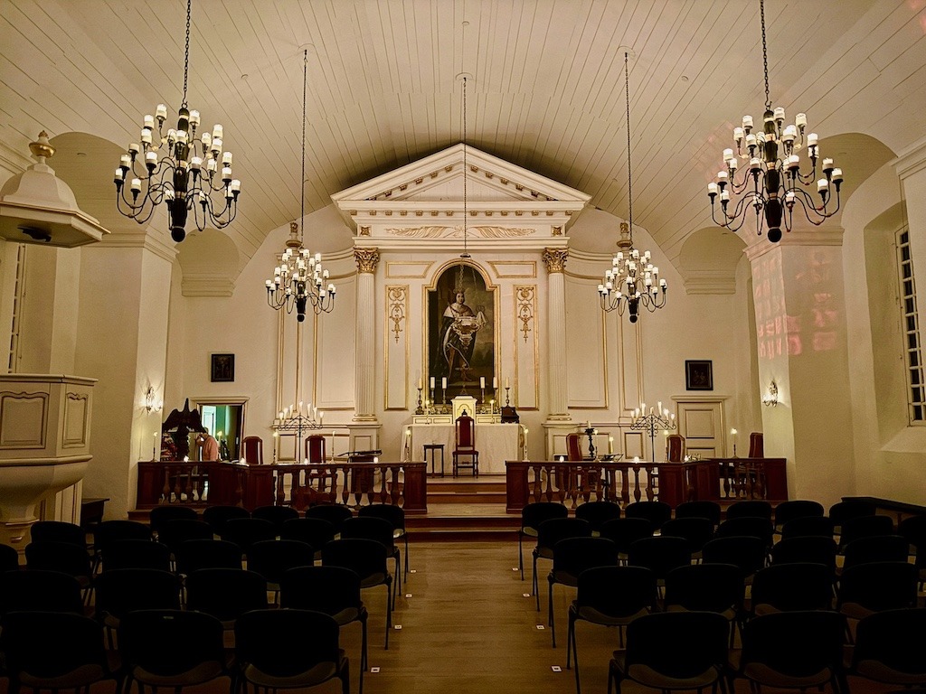 Historic chapel-style concert venue lit by chandeliers, prepared for a Celtic Colours International Festival performance.