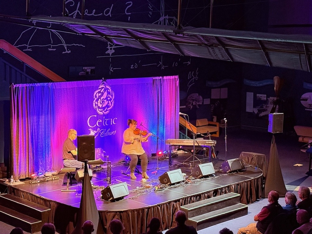 Musician playing fiddle on stage under purple lights at a Celtic Colours International Festival concert in Cape Breton
