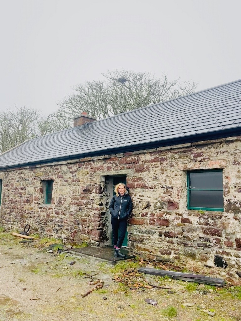 A woman stands outside a bothy at Wild Nephin National Park