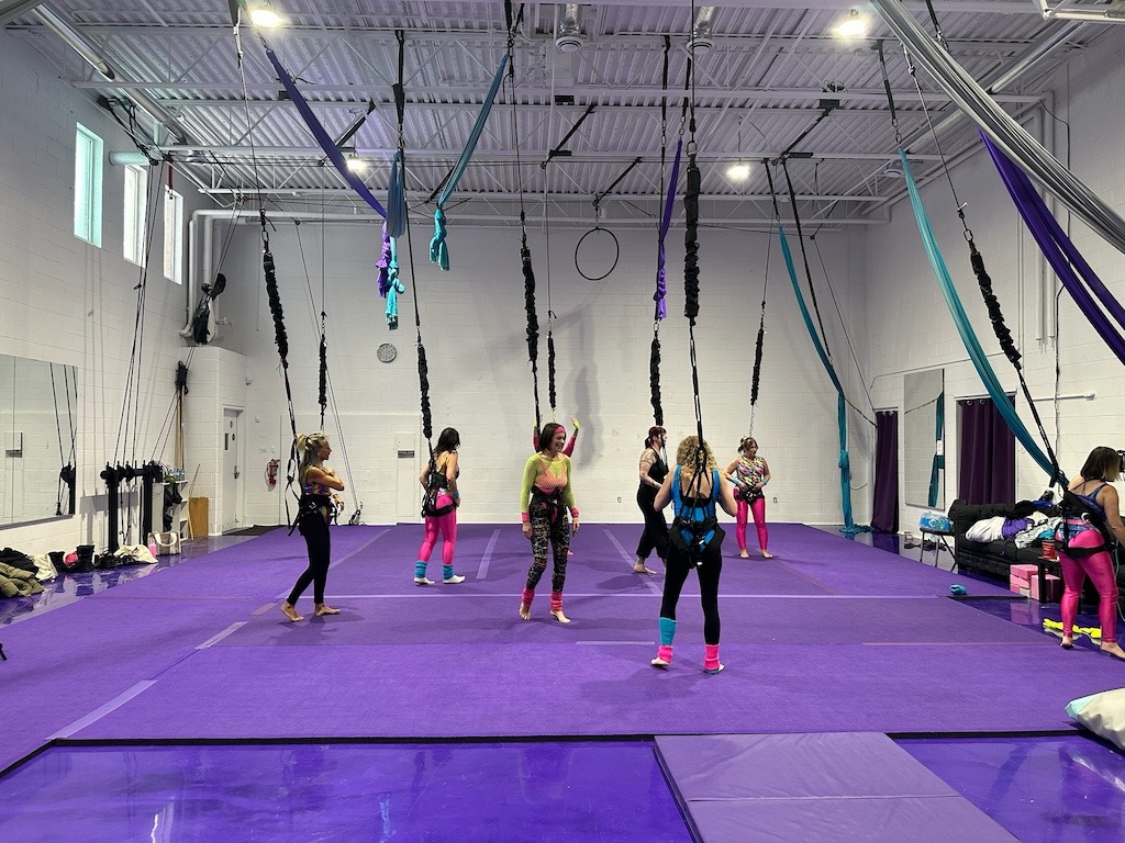 Group of women in neon 80s workout gear at aerial fitness studio during winter girls weekend in Crystal Beach Ontario