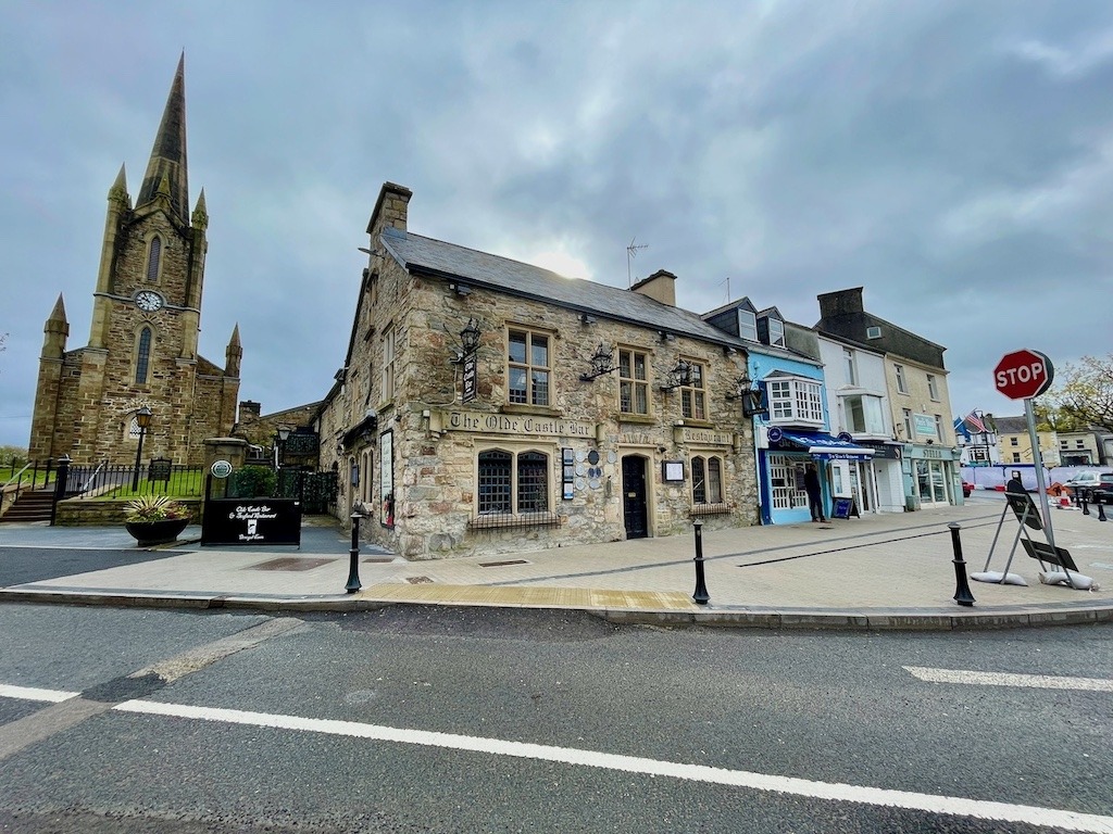 The Olde Castle Bar and Restaurant on the Diamond in Donegal Town, with a Gothic church spire rising behind it, County Donegal, Ireland