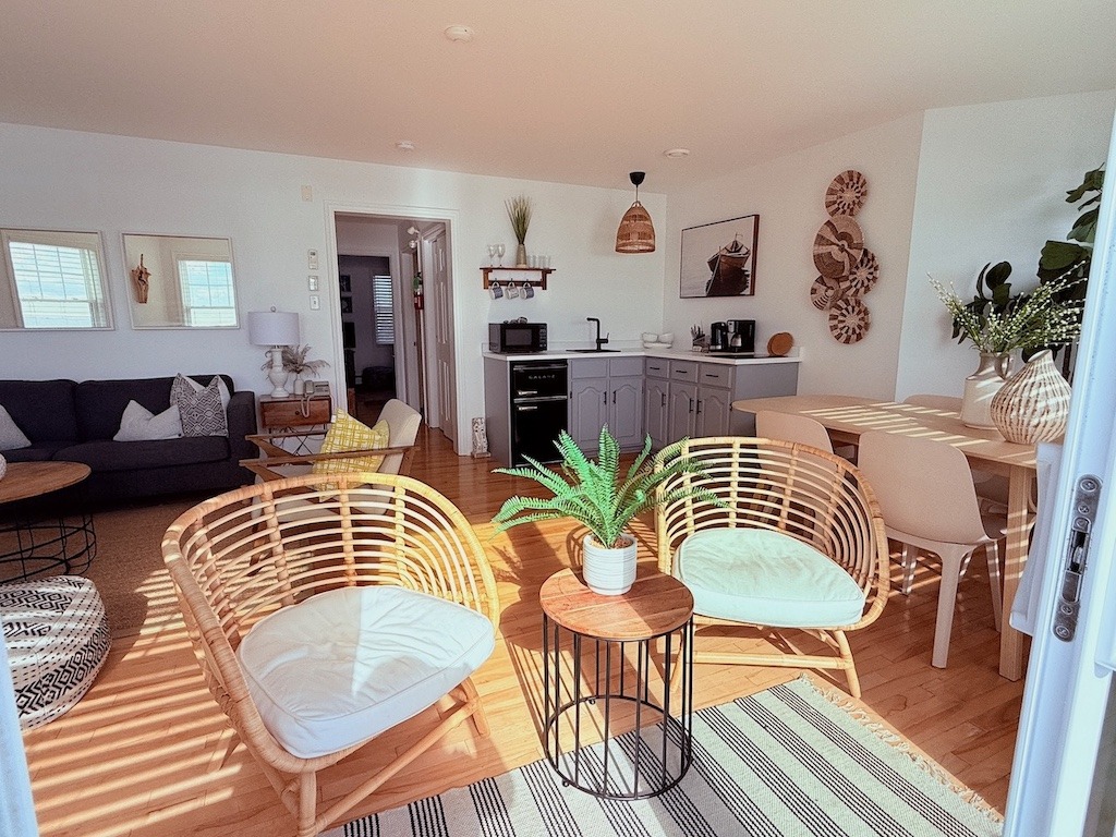 Bright and airy suite living area at North Star Louisbourg with rattan chairs, kitchenette and hardwood floors flooded with natural light