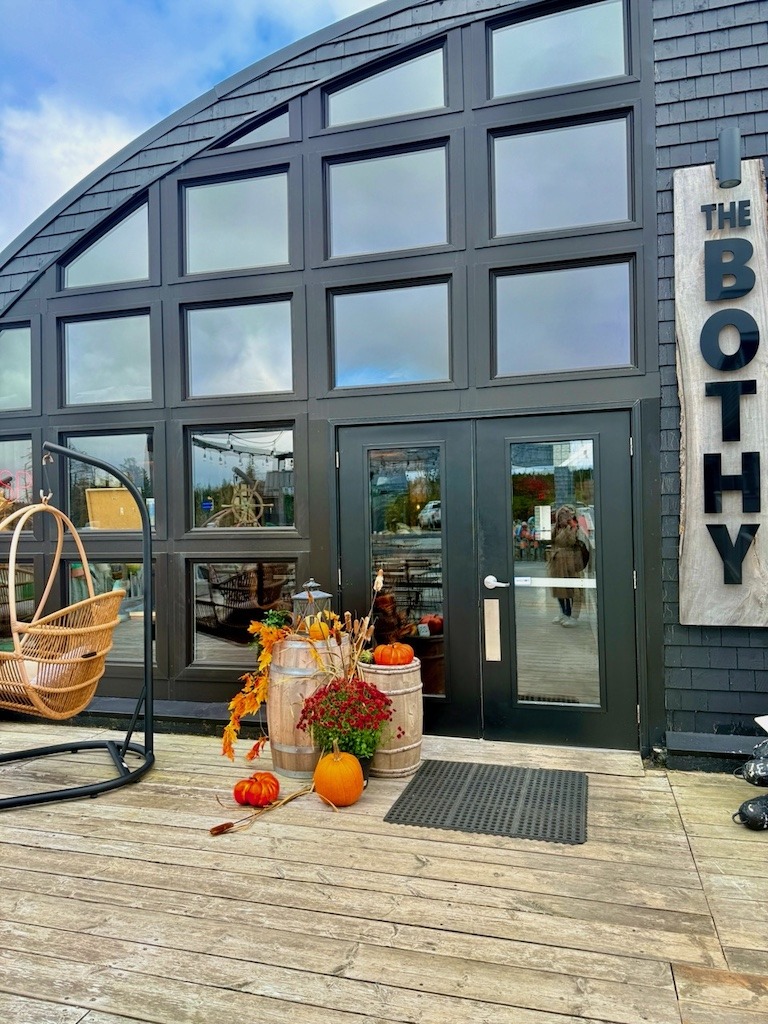 The exterior entrance of The Bothy restaurant at North Star in Cape Breton, a dark Quonset hut with large windows and fall pumpkin decorations