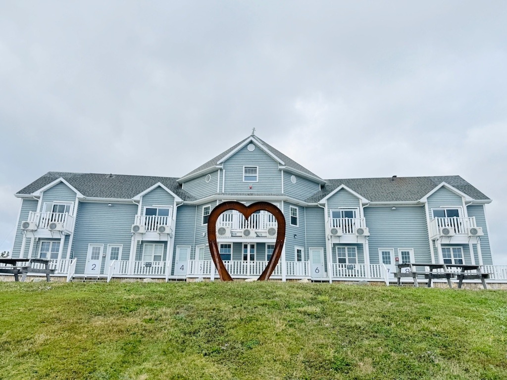 The exterior of North Star Louisbourg hotel with a large Corten steel heart sculpture on the front lawn