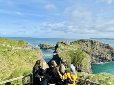 A group of travellers looking out over Carrick-a-Rede rope bridge and the Causeway Coast, Northern Ireland