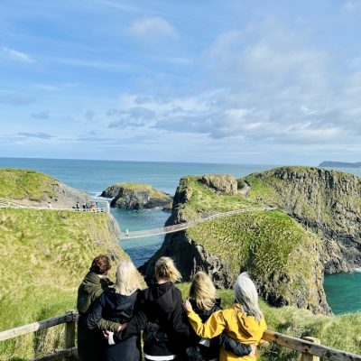 A group of travellers looking out over Carrick-a-Rede rope bridge and the Causeway Coast, Northern Ireland