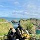 A group of travellers looking out over Carrick-a-Rede rope bridge and the Causeway Coast, Northern Ireland
