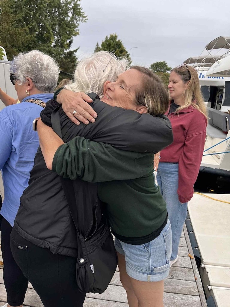 Women hugging at the end of a group travel retreat for women 