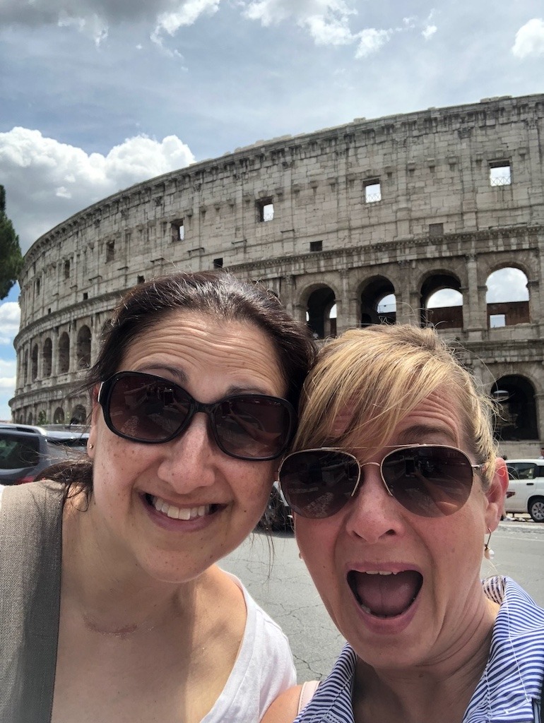 Two women friends laughing outside the Colosseum in Rome