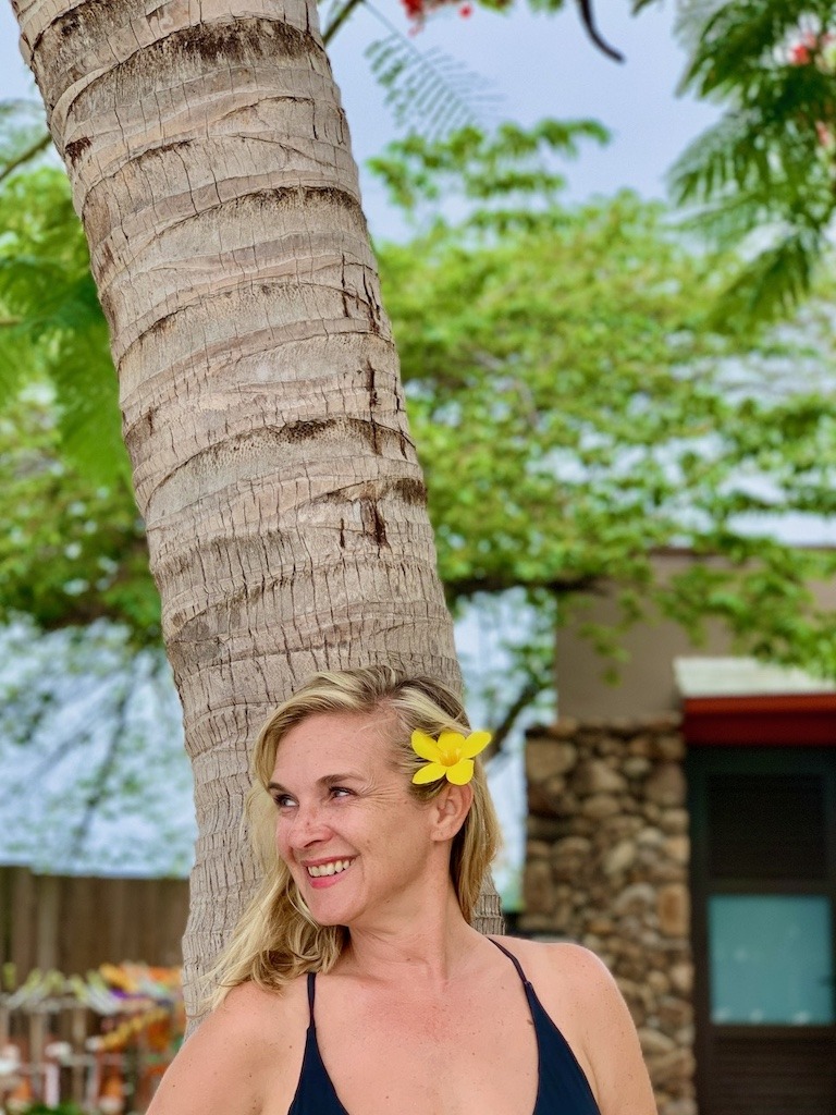 Woman smiling with yellow frangipani flower in hair in Tahiti