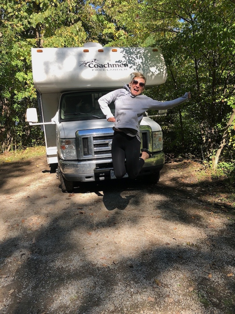 can travel heal a broken heart, Woman jumping for joy in front of RV at Ontario Parks