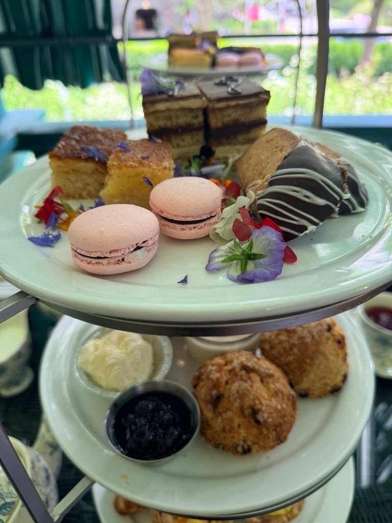 Three-tiered high tea tray at with macaroons scones and opera cake