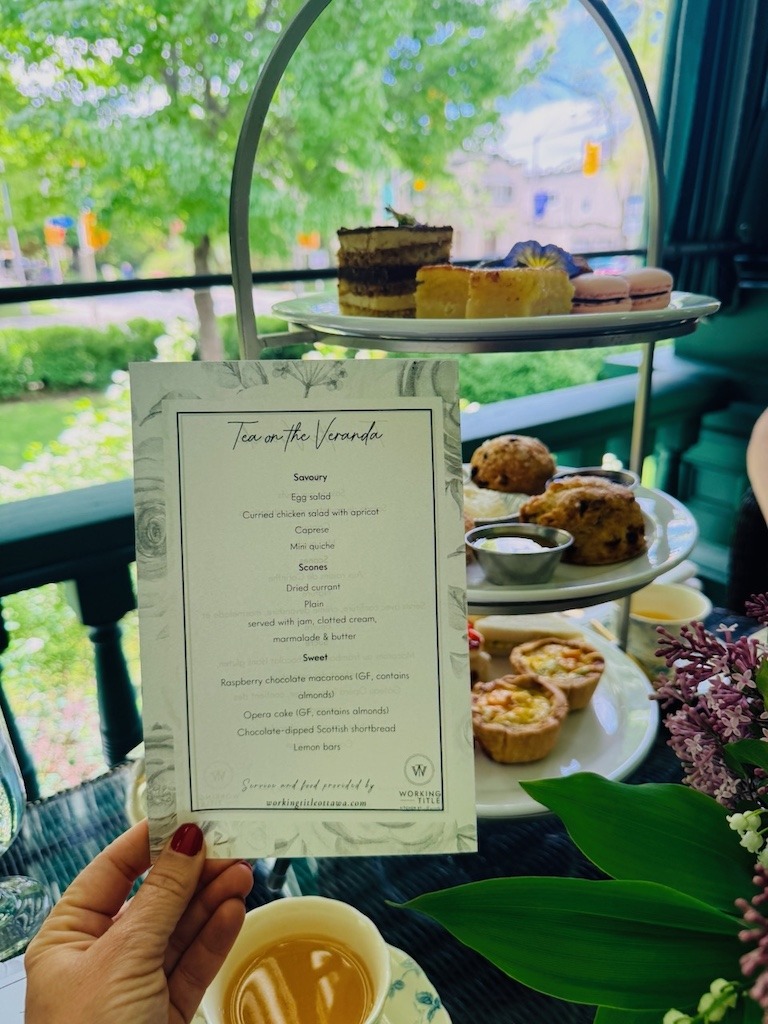 Tea on the Veranda menu held up with three-tiered tray in background at Laurier House Ottawa